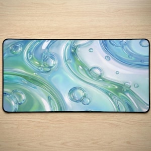 Puede incluir: Alfombrilla de rat&oacute;n rectangular con un dise&ntilde;o abstracto de patrones arremolinados en tonos azules y verdes, que recuerdan al agua. El dise&ntilde;o incluye burbujas y superficies brillantes y reflectantes. Mide unos 30 cm x 20 cm.