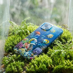 Pode incluir: Uma capa de smartphone com um design subaqu&aacute;tico vibrante, apresentando peixes coloridos, corais e gotas de &aacute;gua. A capa tem um acabamento brilhante e est&aacute; sobre um fundo de musgo verde.