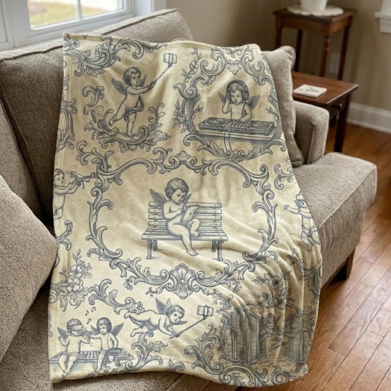 May include: A cream-colored throw blanket with a repeating pattern of cherubs in various poses, including using a tablet and taking selfies. The cherubs are in a gray-blue color, set against a backdrop of ornate scrollwork.
