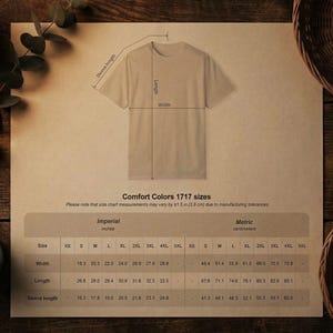 May include: A tan t-shirt laid flat, with measurements for width, length, and sleeve length. The size chart includes imperial measurements in inches and metric measurements in centimeters. The text "Comfort Colors 1717 sizes" is visible.