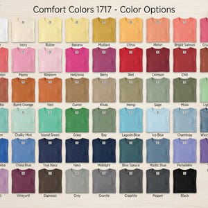 May include: A color chart of Comfort Colors 1717 t-shirts, showcasing a wide array of hues. The image displays a grid of various colors, including white, ivory, yellow, pink, red, blue, and green. Each shirt is neatly folded, with the color name displayed below.
