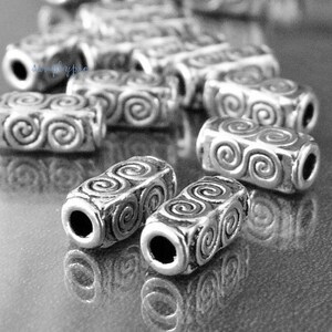 Peut inclure: Perles en m&eacute;tal argent&eacute; avec un motif en spirale. Les perles sont cylindriques et ont une finition lisse et polie.