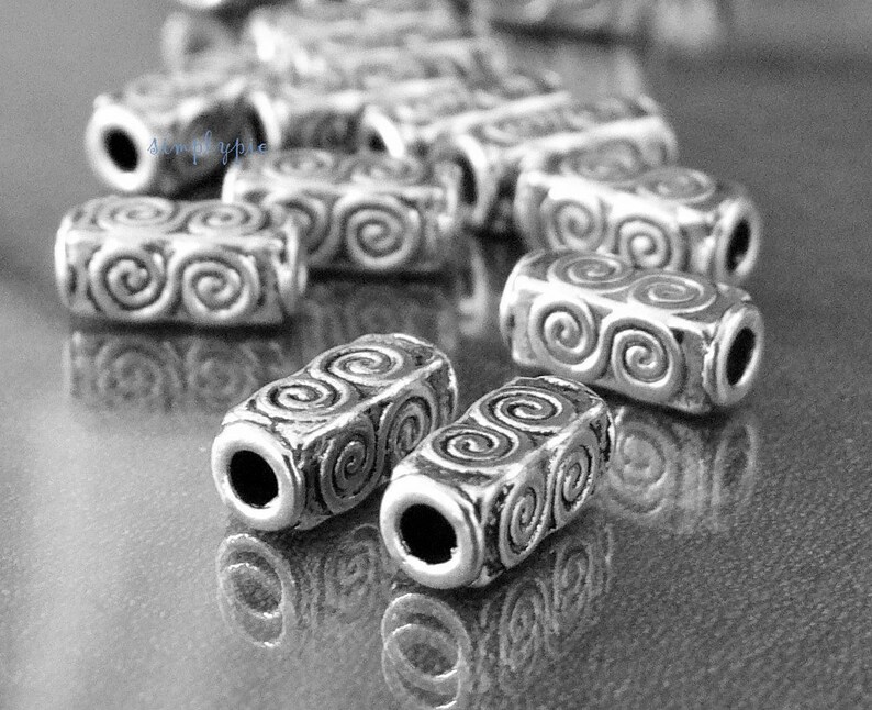 Peut inclure: Perles en m&eacute;tal argent&eacute; avec un motif en spirale. Les perles sont cylindriques et ont une finition lisse et polie.