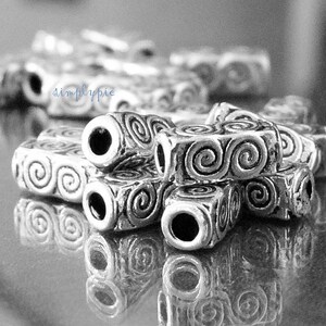 Peut inclure: Perles en m&eacute;tal argent&eacute; avec un motif en spirale. Les perles sont empil&eacute;es les unes sur les autres et ont un trou au centre.