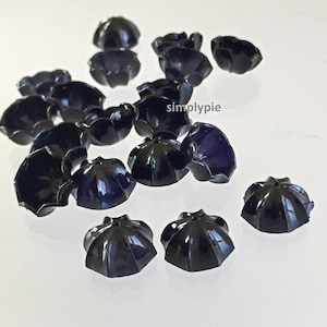 Peut inclure: Une collection de 15 embellissements en plastique noir en forme de fleur. Les embellissements ont une finition brillante et mesurent environ 2,5 cm de diamètre.