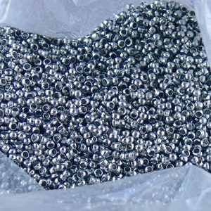 Puede incluir: Una imagen de primer plano de una gran cantidad de cuentas de metal de color plateado en una bolsa de pl&aacute;stico transparente.