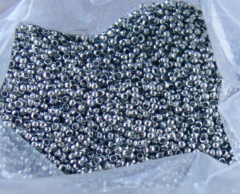 Puede incluir: Una imagen de primer plano de una gran cantidad de cuentas de metal de color plateado en una bolsa de pl&aacute;stico transparente.