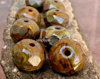 May include: Close-up of several faceted beads in shades of brown, green, and gold. The beads have a glossy finish and a hole running through the center. The word "simplypie" is visible on the surface.