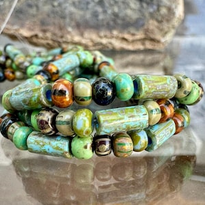 Peut inclure: Un bracelet multi-brins composé de diverses perles en verre dans des tons turquoise, vert citron, marron et noir. Les perles présentent des formes cylindriques et sphériques avec des motifs marbrés, tachetés et rayés, enfilées sur un cordon.