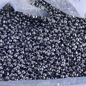 Puede incluir: Una vista de cerca de una gran cantidad de peque&ntilde;as cuentas redondas de metal de color plateado. Las cuentas est&aacute;n dispuestas en un patr&oacute;n aleatorio y parecen estar en una bolsa de pl&aacute;stico.