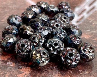 Könnte beinhalten: Ein Haufen dunkler, irisierender Glasperlen mit einem facettierten, rosenartigen Design. Die Perlen haben einen metallischen Glanz und sind etwa 2,5 cm im Durchmesser.