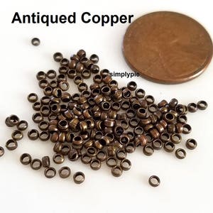 Puede incluir: Un mont&oacute;n grande de peque&ntilde;os anillos de salto de cobre antiguo. Los anillos tienen aproximadamente 4 mm de di&aacute;metro y est&aacute;n dispersos sobre una superficie blanca. Se incluye una moneda de un c&eacute;ntimo de euro para comparar el tama&ntilde;o.