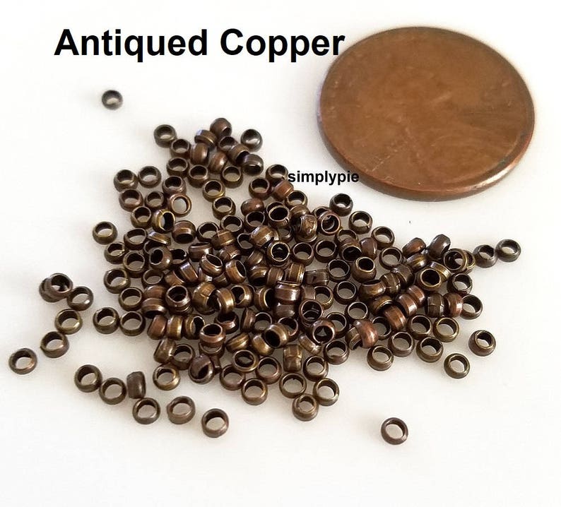 Puede incluir: Un mont&oacute;n grande de peque&ntilde;os anillos de salto de cobre antiguo. Los anillos tienen aproximadamente 4 mm de di&aacute;metro y est&aacute;n dispersos sobre una superficie blanca. Se incluye una moneda de un c&eacute;ntimo de euro para comparar el tama&ntilde;o.