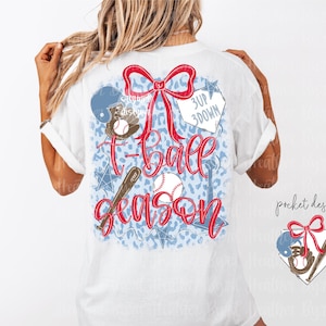 Peut inclure: T-shirt blanc avec un motif sur le thème du baseball. Le motif comprend un nœud rouge, une batte de baseball, une balle de baseball et les mots "T-ball season" en script rouge. Le fond a un motif bleu et blanc avec des étoiles.