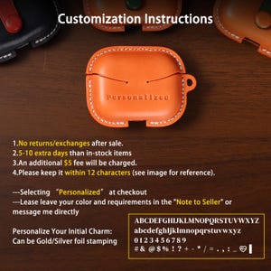 May include: An orange leather protective case for wireless earbuds featuring white contrast stitching and the word Personalized embossed on the front. The case includes a side loop and a snap closure, with text instructions for customisation visible.