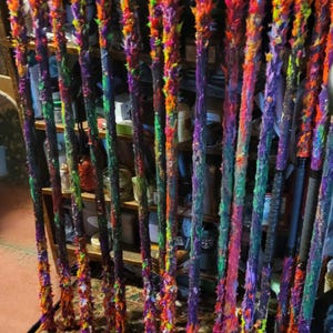 May include: A collection of colorful, multi-colored, and brightly colored wooden staffs with a variety of textures. The staffs are arranged in a row and are leaning against a shelf.