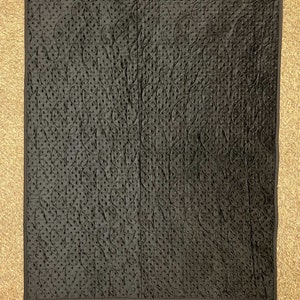 K&ouml;nnte beinhalten: Schwarzer gesteppter Stoff mit einem dekorativen Muster aus Wirbeln und Punkten.