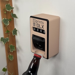 Könnte beinhalten: Ein an der Wand montierter Flaschenöffner mit einer strukturierten, beigefarbenen Oberfläche und schwarzem Rand. Der Öffner hat einen Zähler mit dem Text "3Dprints DLX" und einer Reihe von Zahlen. Eine braune Flasche mit rotem Verschluss wird geöffnet.