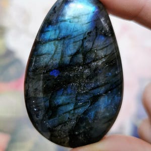 Könnte beinhalten: Ein glatter, ovaler Labradorit-Edelstein mit einem dunkelblauen und schwarzen, irisierenden Schimmer.