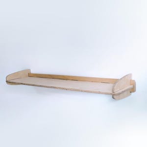 May include: A light wood shelf with rounded edges and a simple design. The shelf is mounted to a white wall.