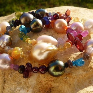 May include: A multi-colored pearl necklace with a variety of gemstones, including pearls, garnets, and opals. The necklace is made of a mix of natural and cultured pearls.