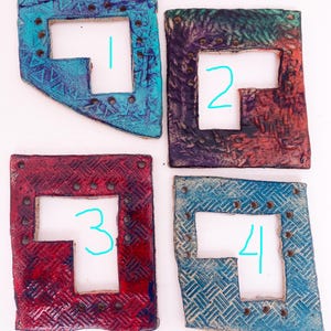 May include: Four ceramic tiles with different colored glazes and a T-shaped cutout. Each tile has a number written on it in turquoise blue.