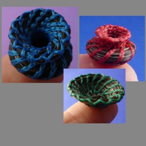 May include: Three miniature woven baskets, one blue, one red, and one green. The baskets are made of natural fibers and have a unique, swirling design.