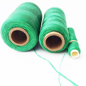May include: Three spools of green thread, two larger spools and one smaller spool. The thread is wound around cardboard spools.
