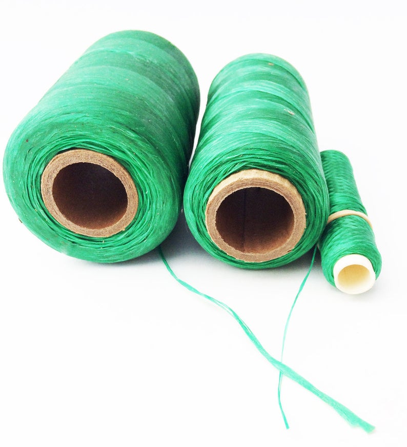 May include: Three spools of green thread, two larger spools and one smaller spool. The thread is wound around cardboard spools.