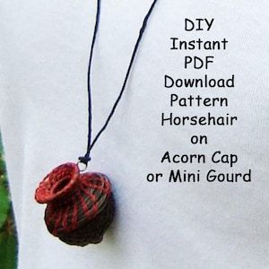 Puede incluir: Un colgante tejido en marrón oscuro y rojo que cuelga de un cordón negro fino. El texto dice: DIY Instant PDF Download Pattern Horsehair on Acorn Cap or Mini Gourd. El colgante presenta una base redondeada y texturizada con una abertura superior circular.