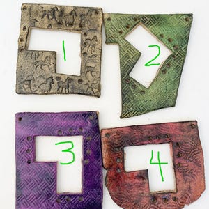 May include: Four ceramic tiles with different patterns and colors. Each tile has a cutout in the shape of a letter, numbered 1 through 4.