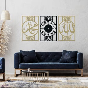 Może przedstawiać: Trzy dekoracyjne panele ścienne z geometrycznymi wzorami. Panel środkowy zawiera tarczę zegara z cyframi arabskimi. Panele lewy i prawy zawierają arabską kaligrafię. Panele są zamontowane na szarej ścianie nad niebieską sofą.