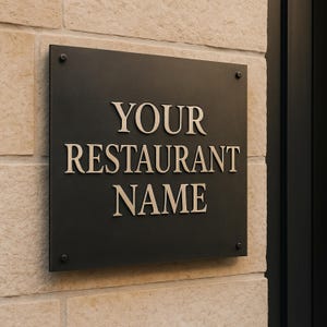 May include: A black rectangular sign with the words "YOUR RESTAURANT NAME" in a serif font. The sign is mounted on a light-colored stone wall with four screws in each corner.
