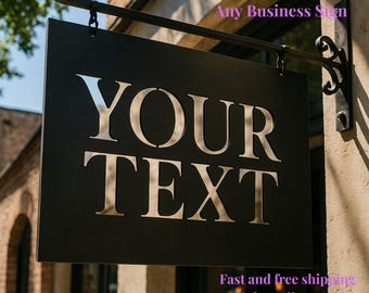 Könnte beinhalten: Ein schwarzes rechteckiges Firmenschild mit den Worten "YOUR TEXT" in Silber, das an einer schwarzen Metallhalterung hängt. Das Schild ist an einem Backsteingebäude angebracht. Der Text "Your Custom Sign Any Business Sign" steht darüber.