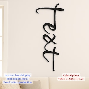 May include: Black metal wall art spelling out the word "text" in a cursive font. The wall decor is mounted on a cream-colored wall. The image also includes the text "Color Options YOUR CUSTOM TEXT".