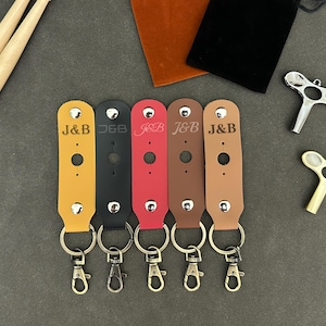 May include: Five leather keychains with silver key rings. Each keychain is brown, black, red, or tan and has the text "J&B" engraved on it.