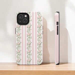 May include: A pink and white striped phone case with a floral design. The case has a black camera cutout and a black border.