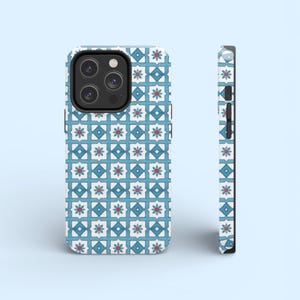 May include: A smartphone case with a geometric pattern. The case features a repeating design of blue squares, white diamonds, and red flower-like shapes. The case is shown from the front and side, showcasing the design and the phone's camera.