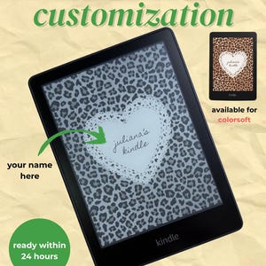 Peut inclure: Liseuse Kindle noire avec un écran de verrouillage personnalisé. L'écran affiche un motif léopard et un cœur blanc avec l'inscription "juliana's kindle". Le texte "kindle & kobo lock screen customization" et "ready within 24 hours" est également visible.