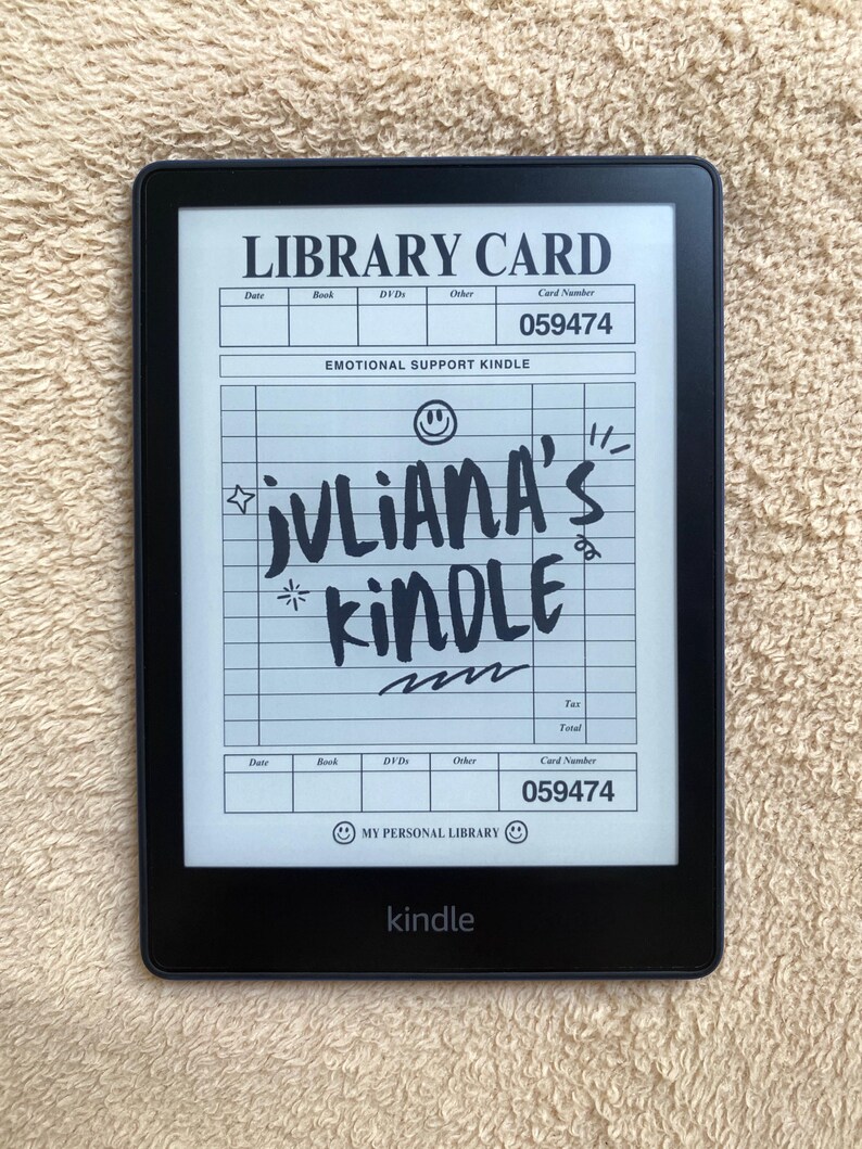 May include: A black Kindle e-reader displaying a handwritten "Library Card" design with the text "JULIANA'S KINDLE." The screen also shows the words "EMOTIONAL SUPPORT KINDLE" and "MY PERSONAL LIBRARY."