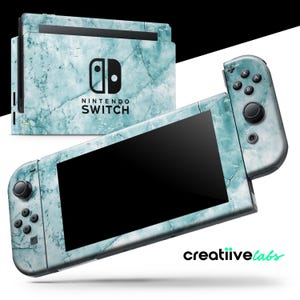 以下が含まれることがあります： ターコイズマーブルデザインのNintendo Switchコンソールとコントローラー。コンソールとコントローラーには黒い画面とボタンがあります。Nintendo Switchのロゴがコンソールに表示されています。「creatiive labs」のブランドも表示されています。