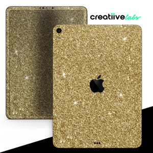 May include: Gold glitter iPad skin with a black Apple logo. The skin is designed to fit the iPad Pro.