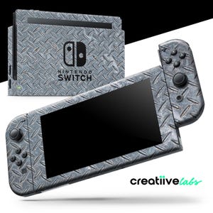 Op de afbeelding: Een Nintendo Switch-console en controllers met een diamantplaatontwerp. De console en controllers zijn grijs met een getextureerde metalen uitstraling. Het Nintendo Switch-logo is zichtbaar.