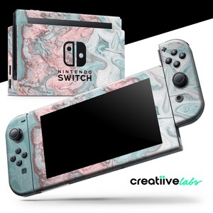 May include: A Nintendo Switch console and controllers with a marble-like design in shades of pink, teal, and white. The console and controllers are displayed against a white background. The text "NINTENDO SWITCH" is visible on the console.