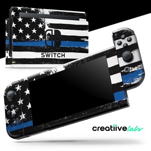 May include: A black Nintendo Switch console and controllers with a distressed American flag design. The design features white stars, black and white stripes, and a blue line. The word "SWITCH" is printed on the console.