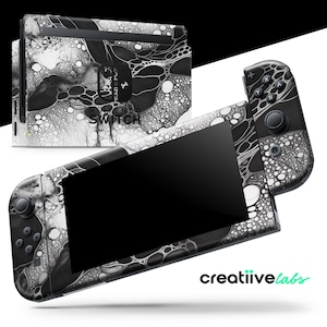 May include: A Nintendo Switch console and controllers with a black and white abstract design. The design features a marbled pattern with a glossy finish. The console and controllers are displayed on a white background.