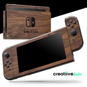 Puede incluir: Una consola Nintendo Switch y su base con acabado de veta de madera. La consola tiene una pantalla negra y botones negros. La base tiene el logotipo de Nintendo Switch. El diseño es de color marrón oscuro.