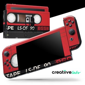 Può includere: Console e dock Nintendo Switch rosse con design a cassetta. Il design include il testo "TAPE LS-DF 90 BSS" e "SWITCH". La console ha pulsanti neri e uno schermo nero. Il marchio "creatiivelabs" è visibile.