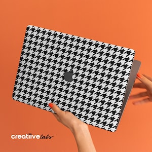 Puede incluir: Una piel para portátil con estampado de pata de gallo en blanco y negro. La piel se aplica a un portátil plateado.