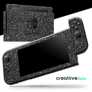 May include: A black Nintendo Switch console and controllers with a speckled design. The console and controllers are black with white speckles. The Nintendo Switch logo is visible on the console. The brand name "creatiive labs" is in the bottom right corner.